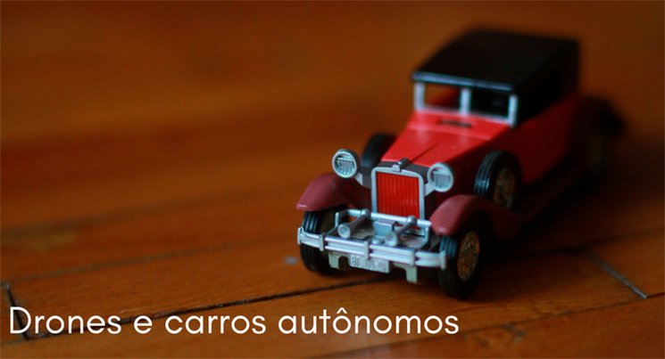 Imagem de uma miniatura de carro vermelho antigo em cima de uma mesa de madeira com a descrição: drones e carros autônomos