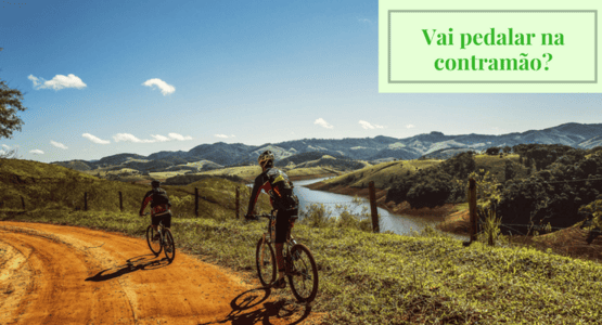 imagem de dois ciclistas pedalando em uma estrada com a farse: vai pedalar na contra mão?