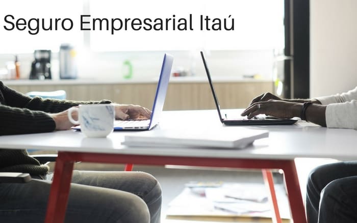 Imagem de dois homens na mesa com o computador com a descrição da imagem: Seguro empresarial Itaú