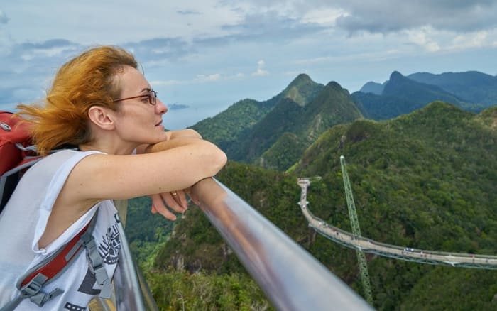 Imagem de mulher curtindo a paisagem para ilustrar post sobre mulheres compram mais seguro viagem