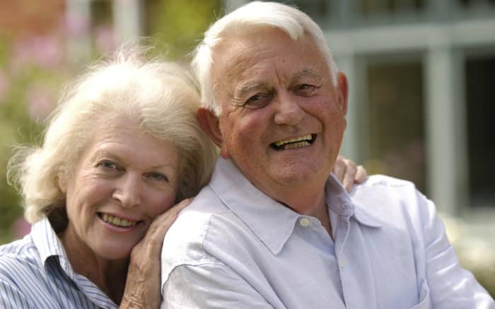 Imagem de casal de idosos sorrindo para ilustrar texto sobre odontogeriatria.