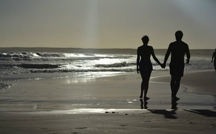 Foto de casal na praia para ilustrar texto sobre lugares para viajar a dois