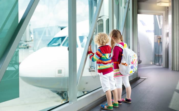 Imagem de duas crianças no aeroporto para ilustrar texto sobre viajar nas férias de julho